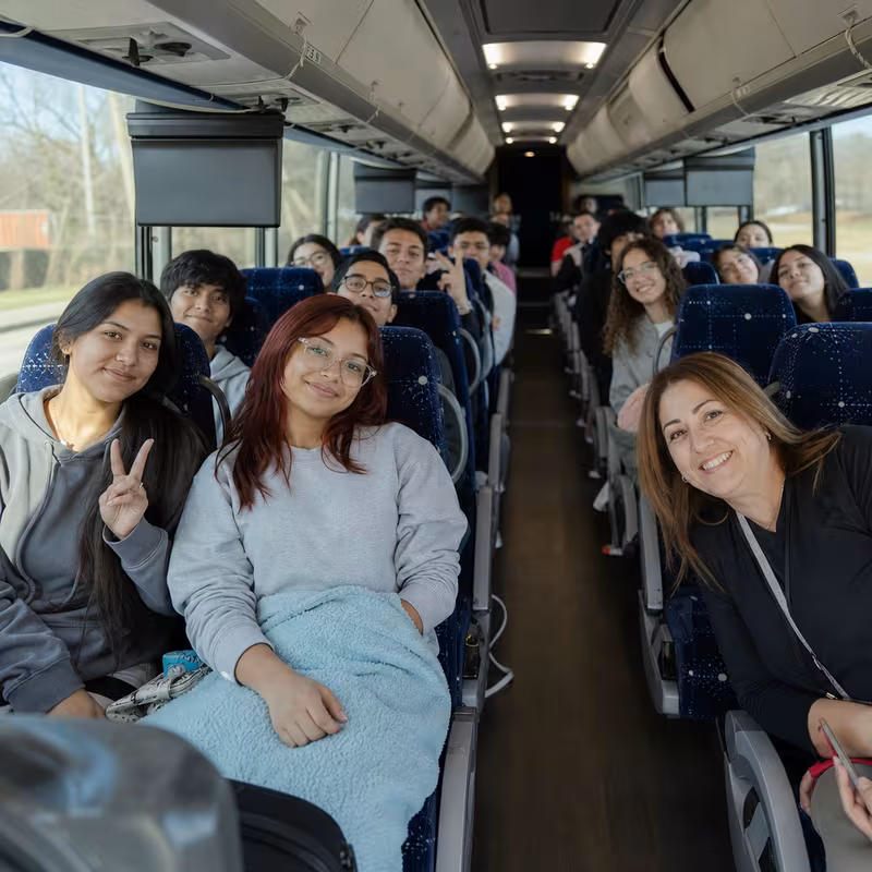 Group boarding a white charter bus for School Transportation transportation in Omaha