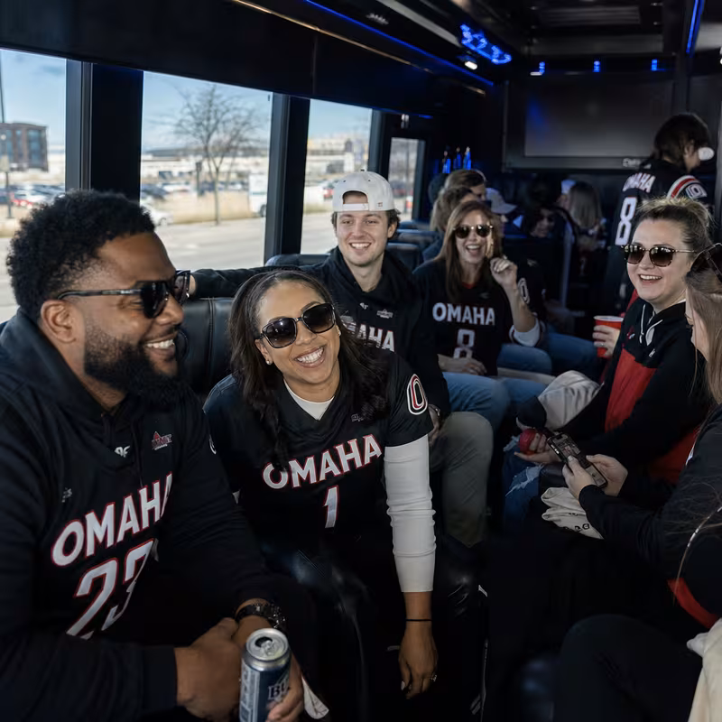 Group boarding a white charter bus for Sporting Event Transportation transportation in Omaha